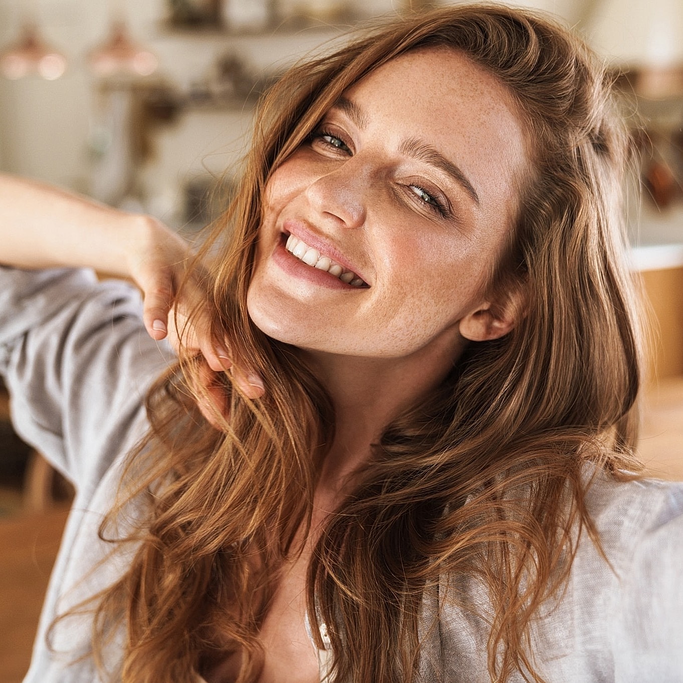 Smiling woman taking a selfie in a cozy setting.
