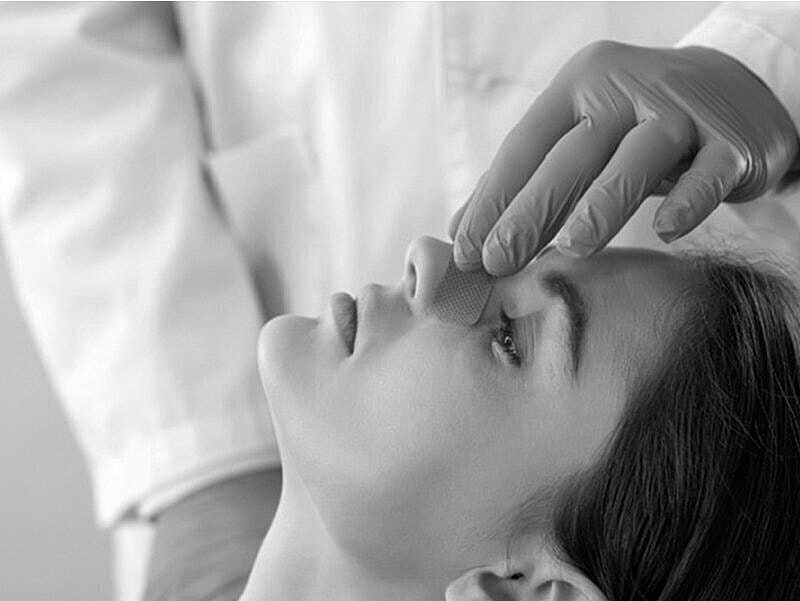 Applying treatment on a woman's nose.