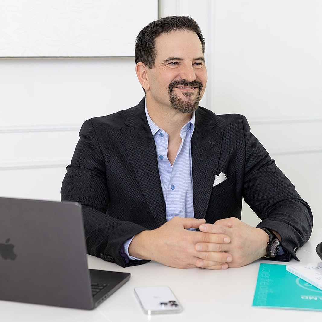 Professional man seated at a desk with laptop.