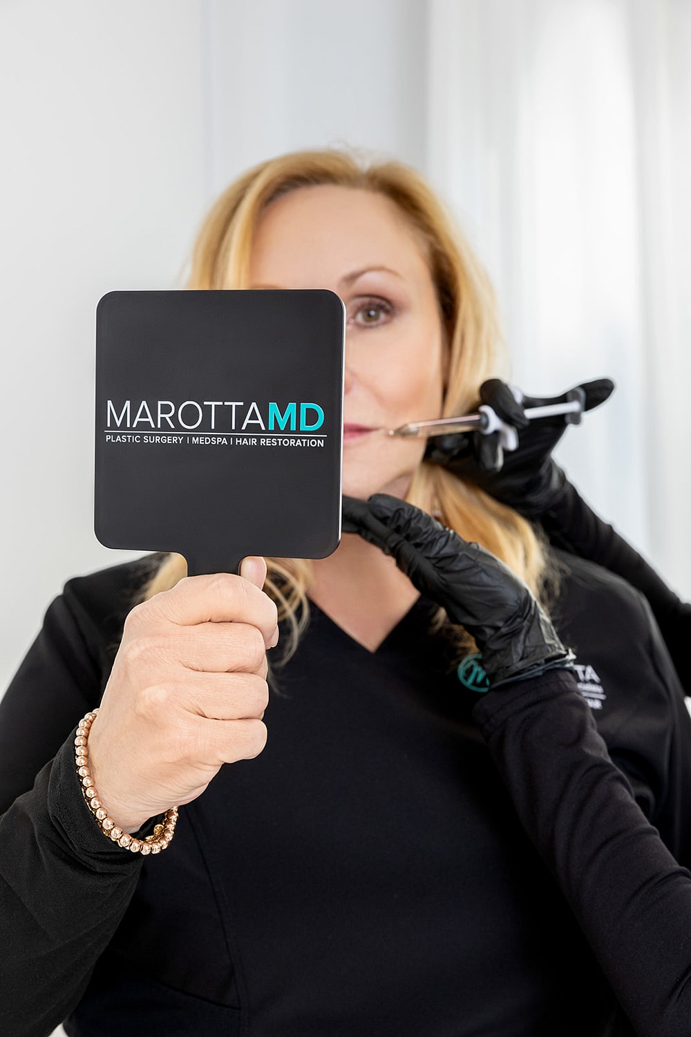 Woman holding mirror during cosmetic procedure.