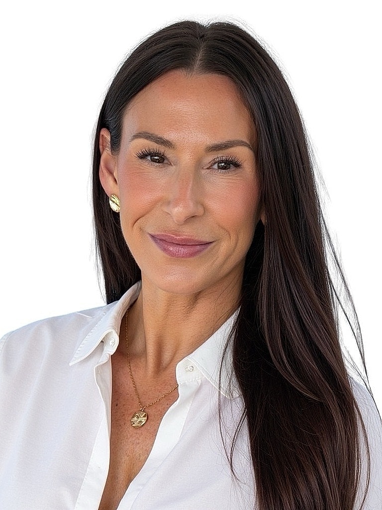 Woman smiling in a white blouse with jewelry.