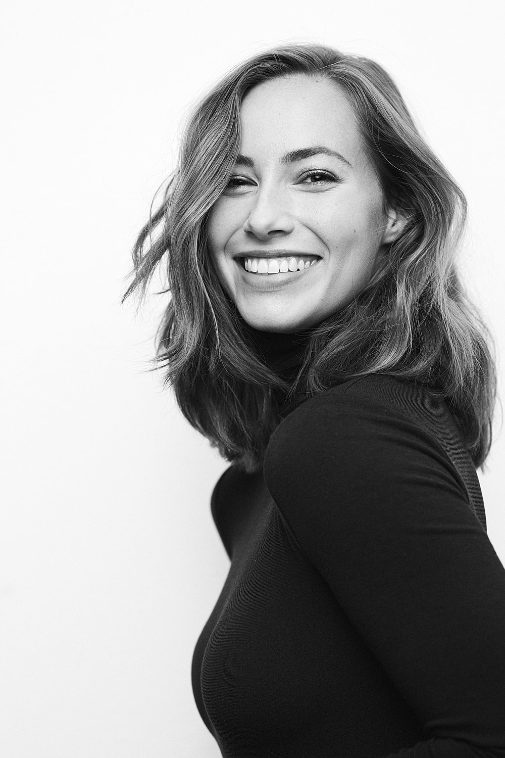 Smiling woman in black turtleneck, profile view.