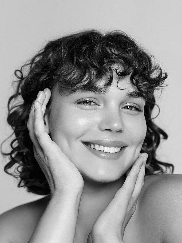 Smiling woman with curly hair in black and white.