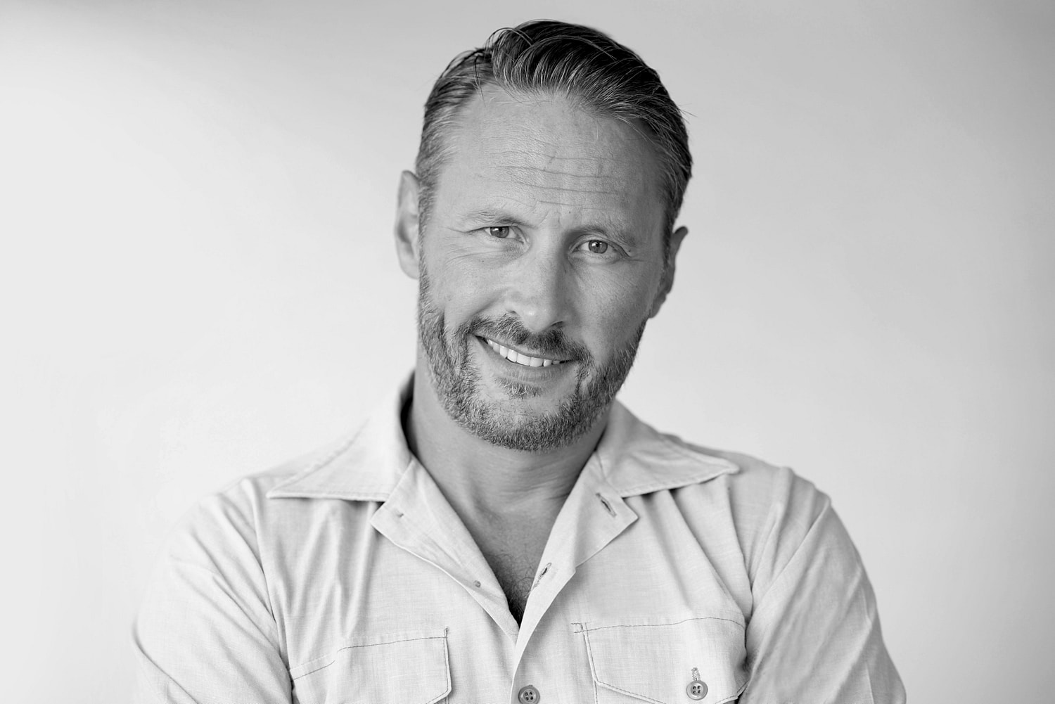 Smiling man with beard in black and white.