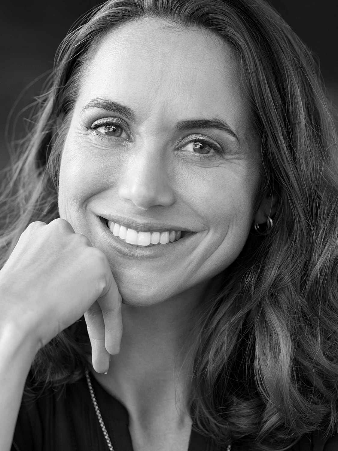 Smiling woman with long hair in black and white.