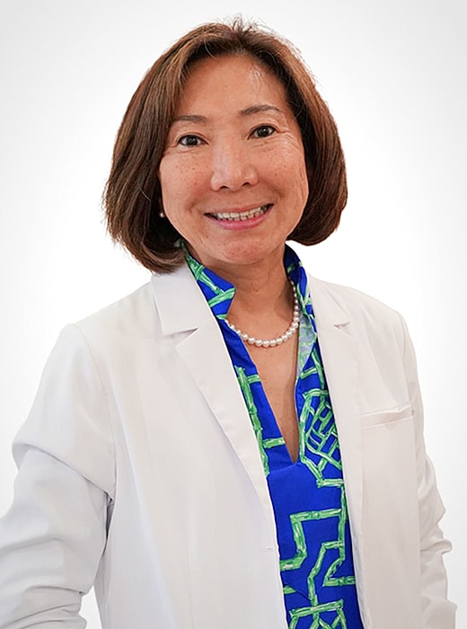 Smiling woman in lab coat and vibrant shirt.